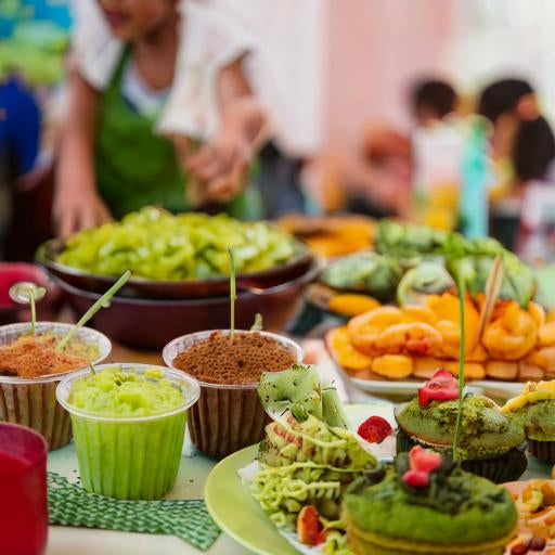 Kids are happily preparing dishes, surrounded by fresh fruits and vegetables, highlighting fun and healthy cooking