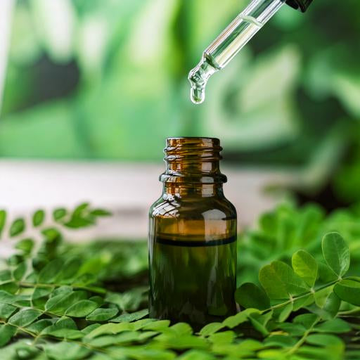 A dropper bottle of moringa drops with fresh moringa leaves, symbolizing eye care and relief from screen time fatigue.